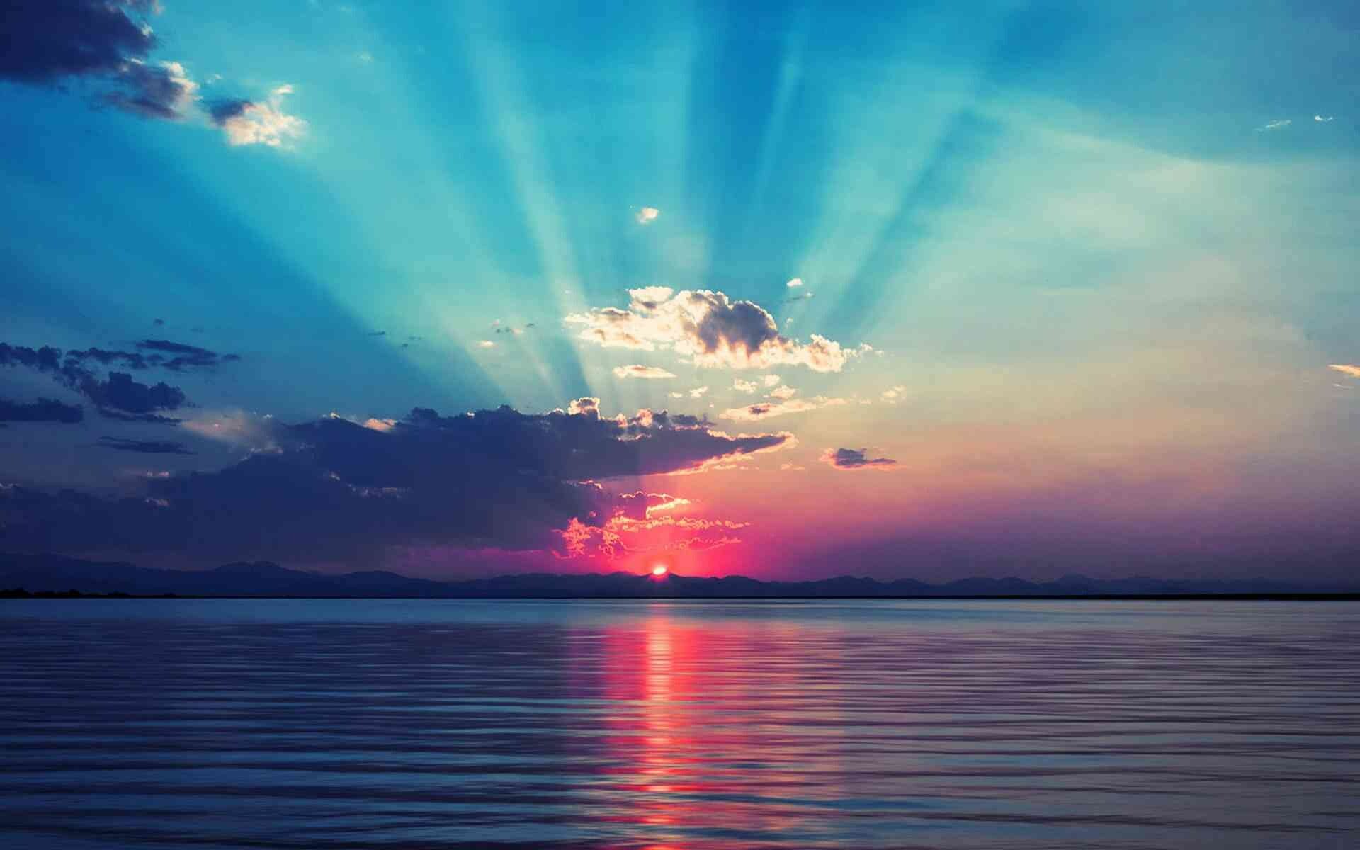 Sunrays bursting through clouds, Red sun on horizon, Blue sky over calm lake Sunrays bursting through clouds, Red sun on horizon, Blue sky over calm lake — 1920×1200 HD wallpaper