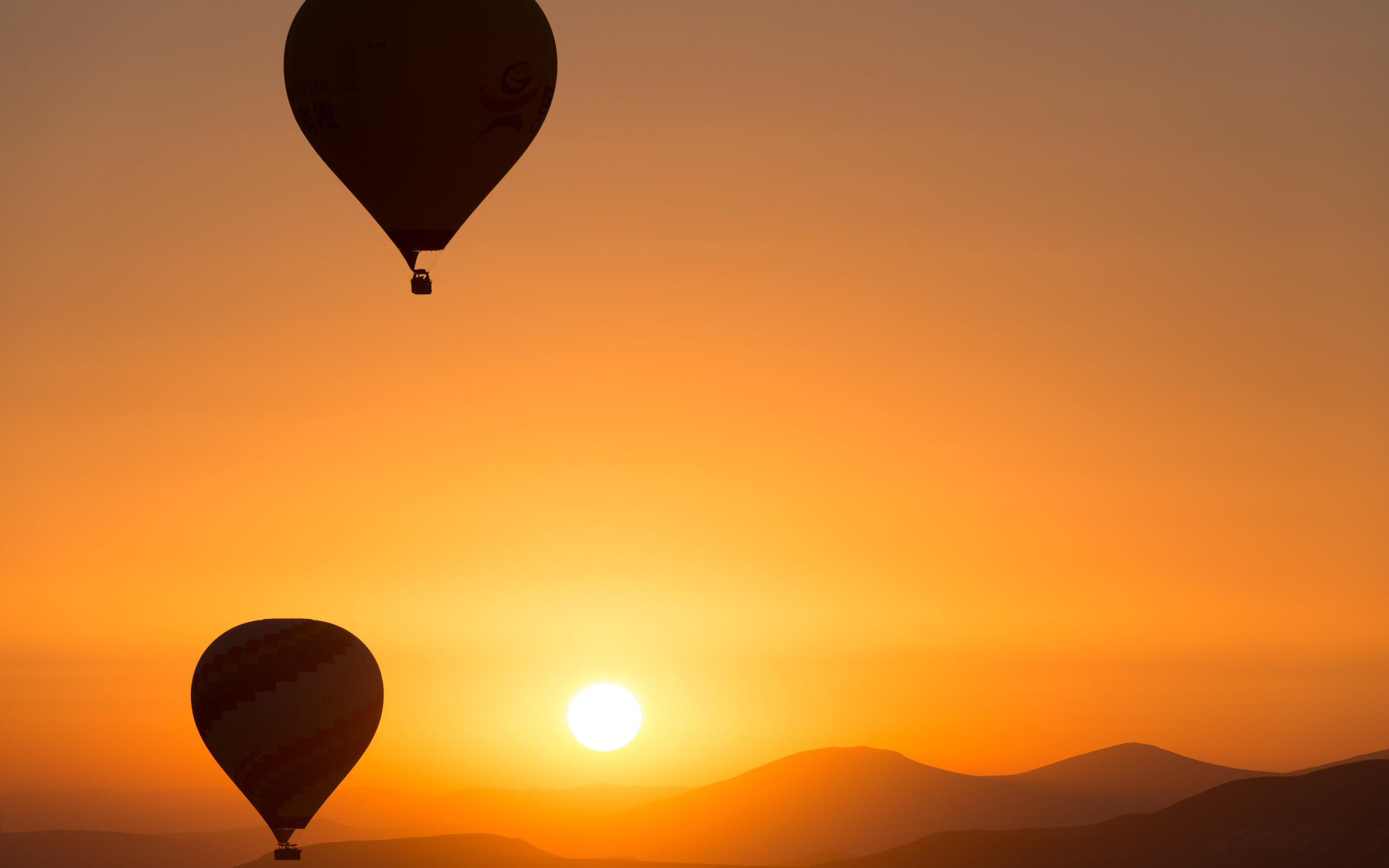 Silhouetted hot air balloons, Orange sunrise over hills, Glowing sun disc Silhouetted hot air balloons, Orange sunrise over hills, Glowing sun disc — 2880×1800 HD wallpaper