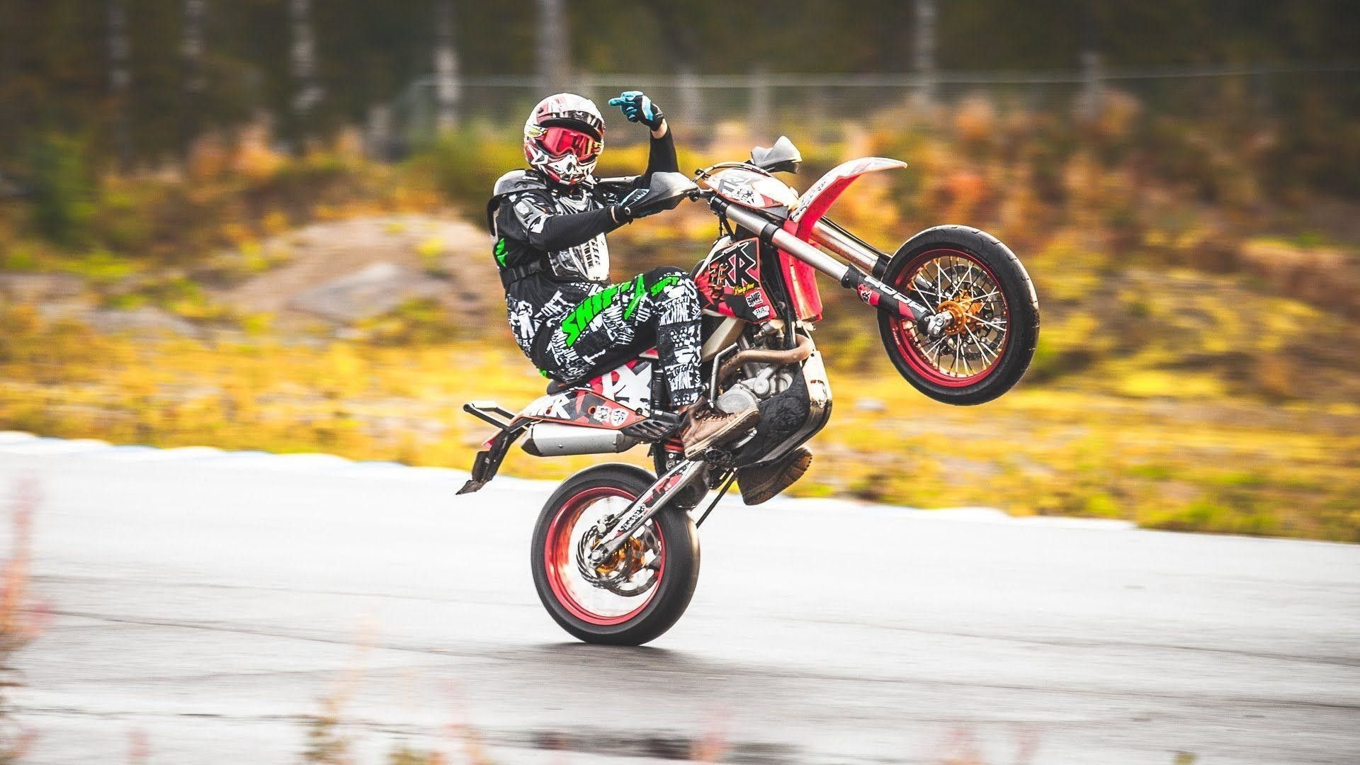 Supermoto wheelie stunt, Graphic leathers rider, Wet asphalt track Supermoto wheelie stunt, Graphic leathers rider, Wet asphalt track — 1920×1080 HD wallpaper