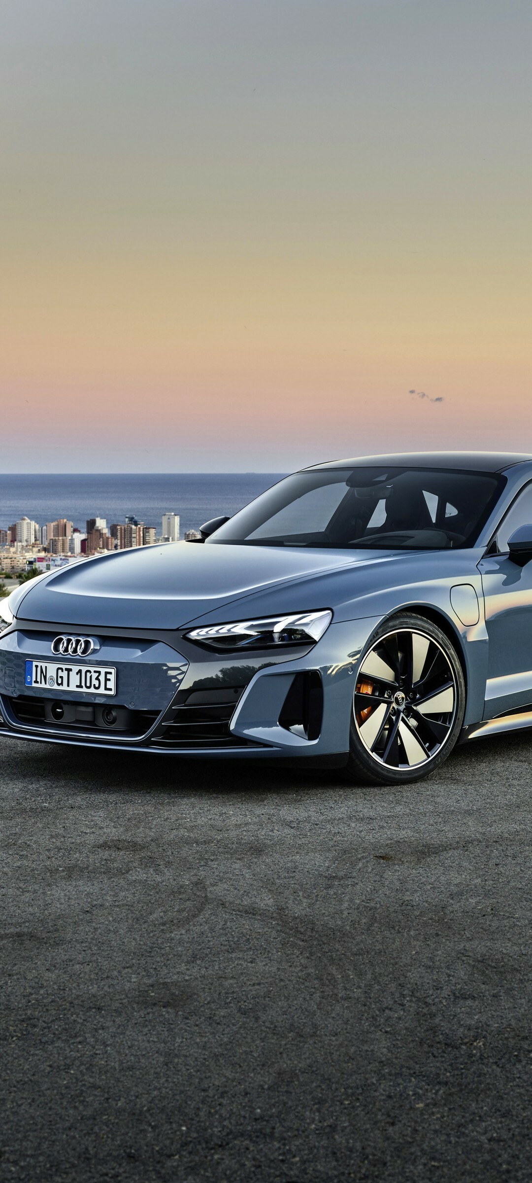 Grey Audi e-tron GT, Coastal city skyline, Orange sunset haze Grey Audi e-tron GT, Coastal city skyline, Orange sunset haze — 1080×2400 HD wallpaper