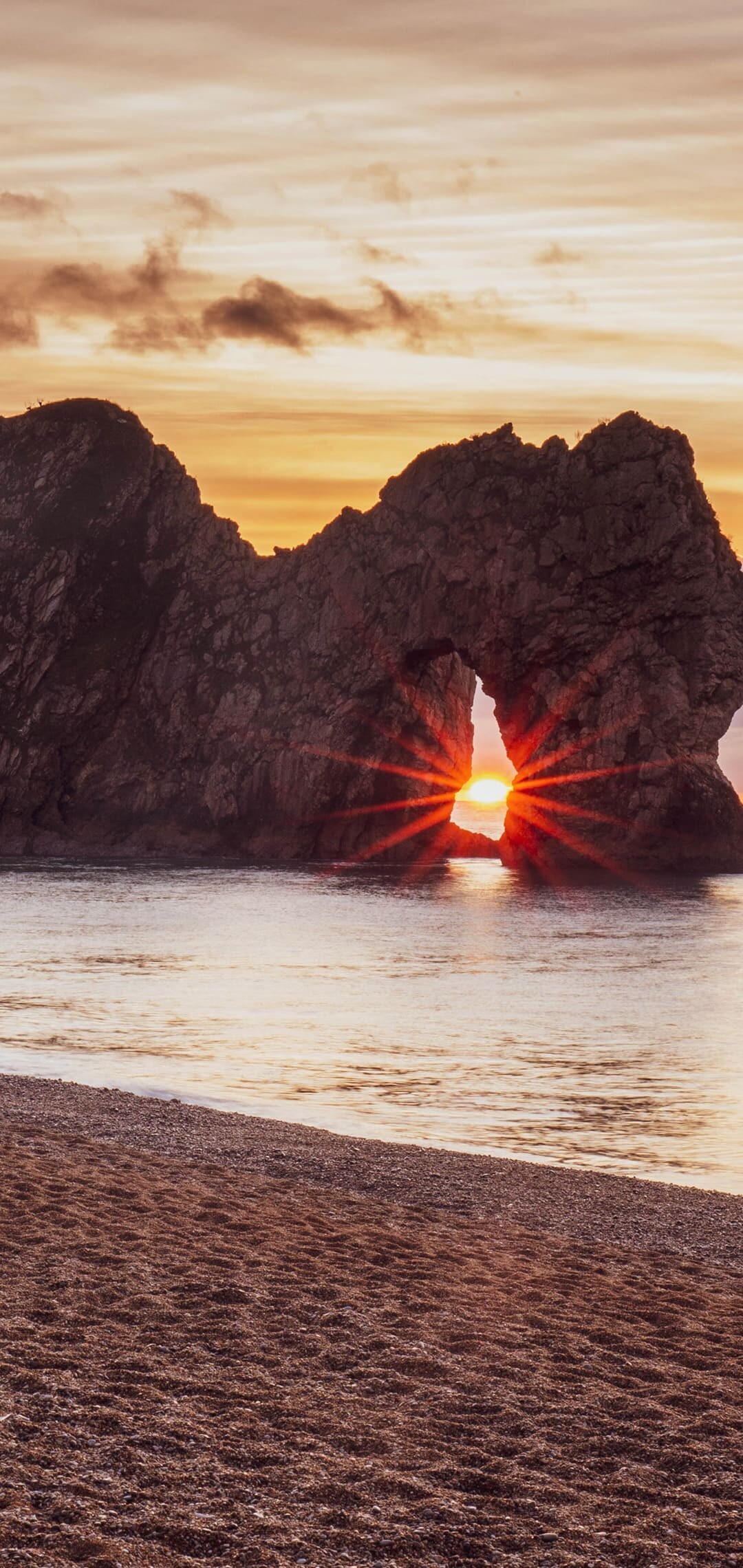 Durdle Door sea arch, Sunburst through rock arch, Pebble beach foreground, Golden sunset sky Durdle Door sea arch, Sunburst through rock arch, Pebble beach foreground, Golden sunset sky — 1080×2280 HD wallpaper