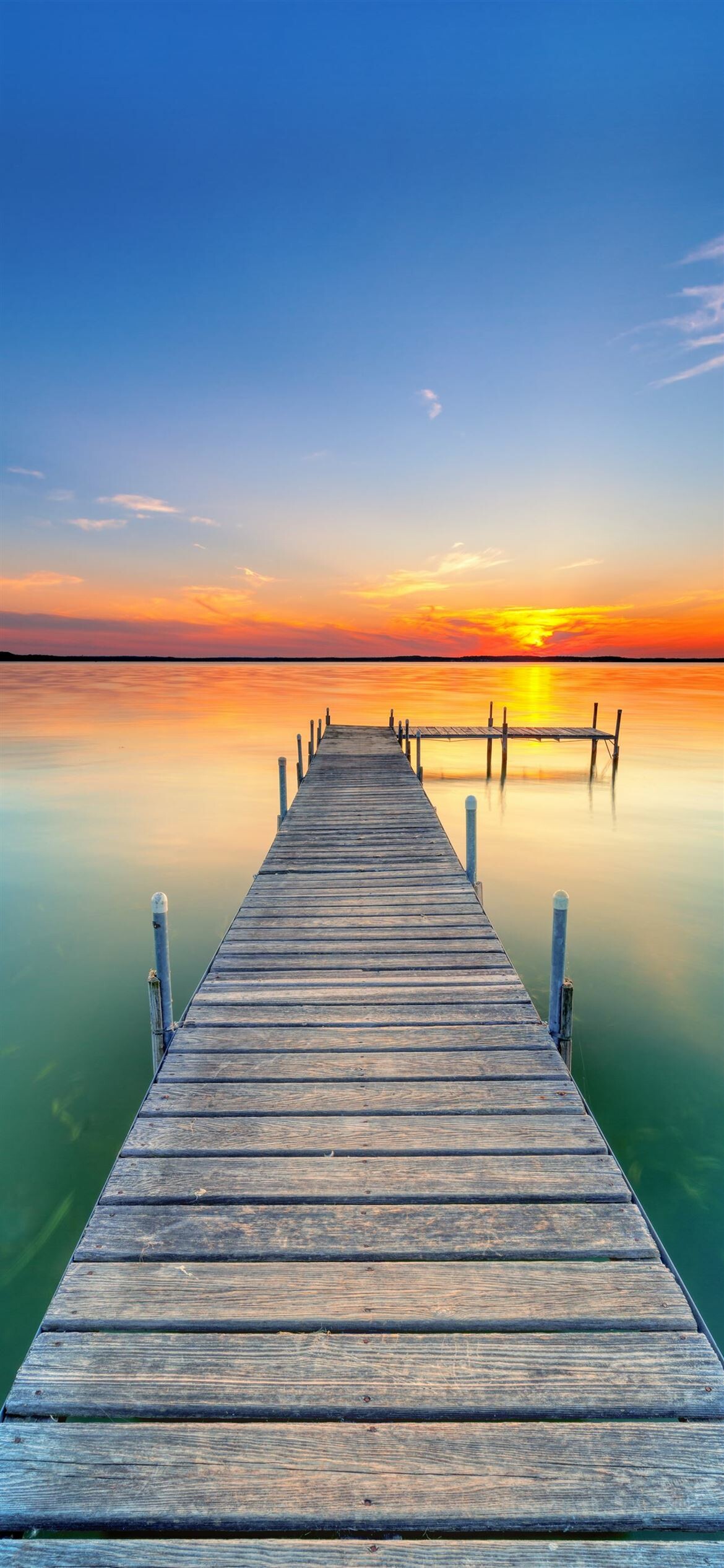 Wooden dock over lake, Orange sunset horizon, Calm reflective water Wooden dock over lake, Orange sunset horizon, Calm reflective water — 1170×2532 HD wallpaper