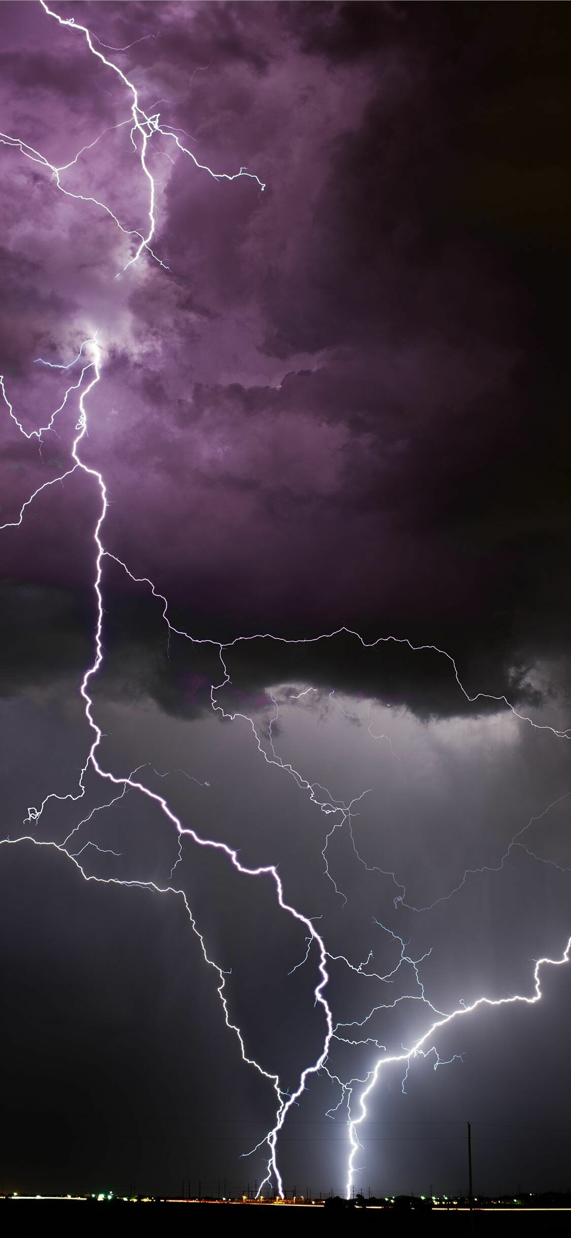 Forked lightning bolts, Purple thunderstorm clouds, Distant city lights Forked lightning bolts, Purple thunderstorm clouds, Distant city lights — 1125×2436 HD wallpaper