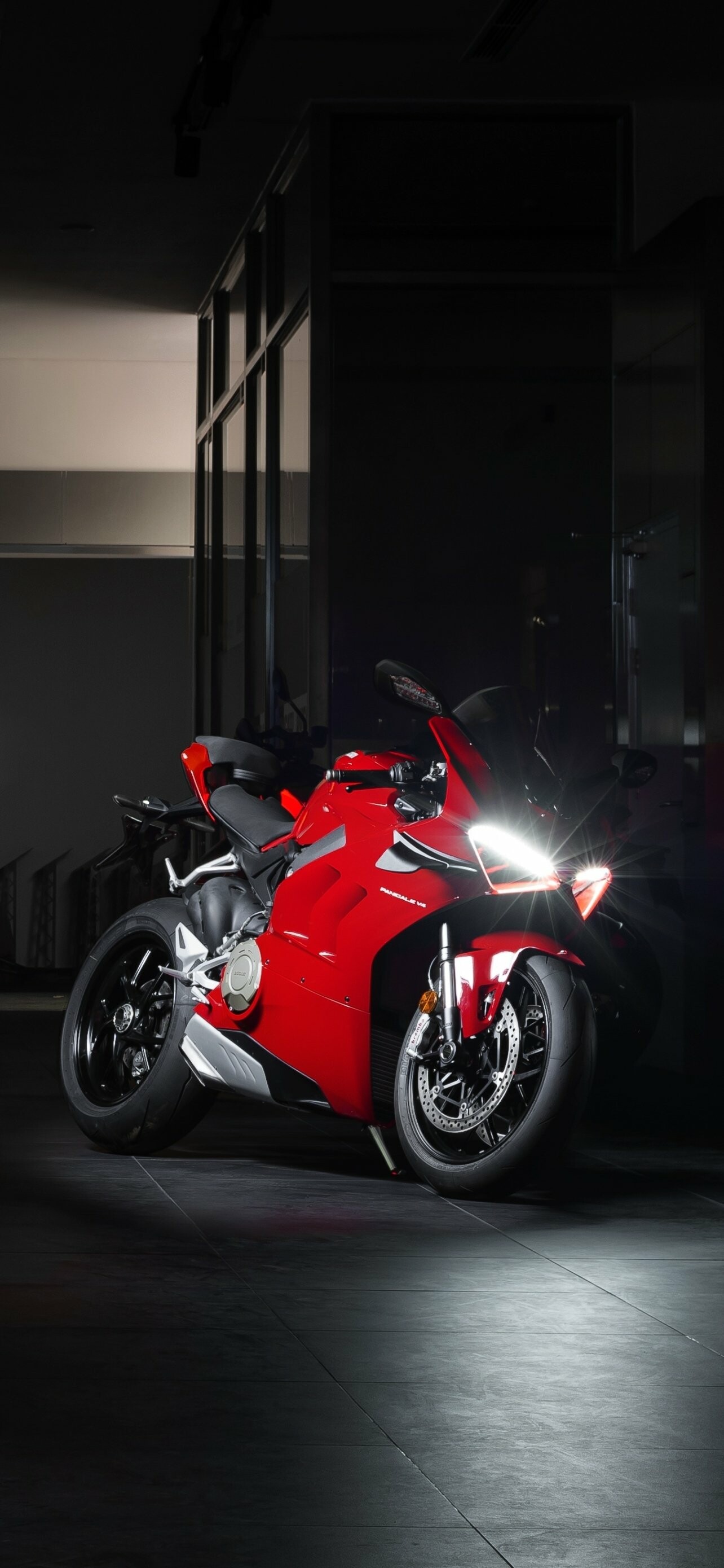 Ducati Panigale V4, Red sportbike headlights, Dark showroom floor Ducati Panigale V4, Red sportbike headlights, Dark showroom floor — 1284×2778 HD wallpaper