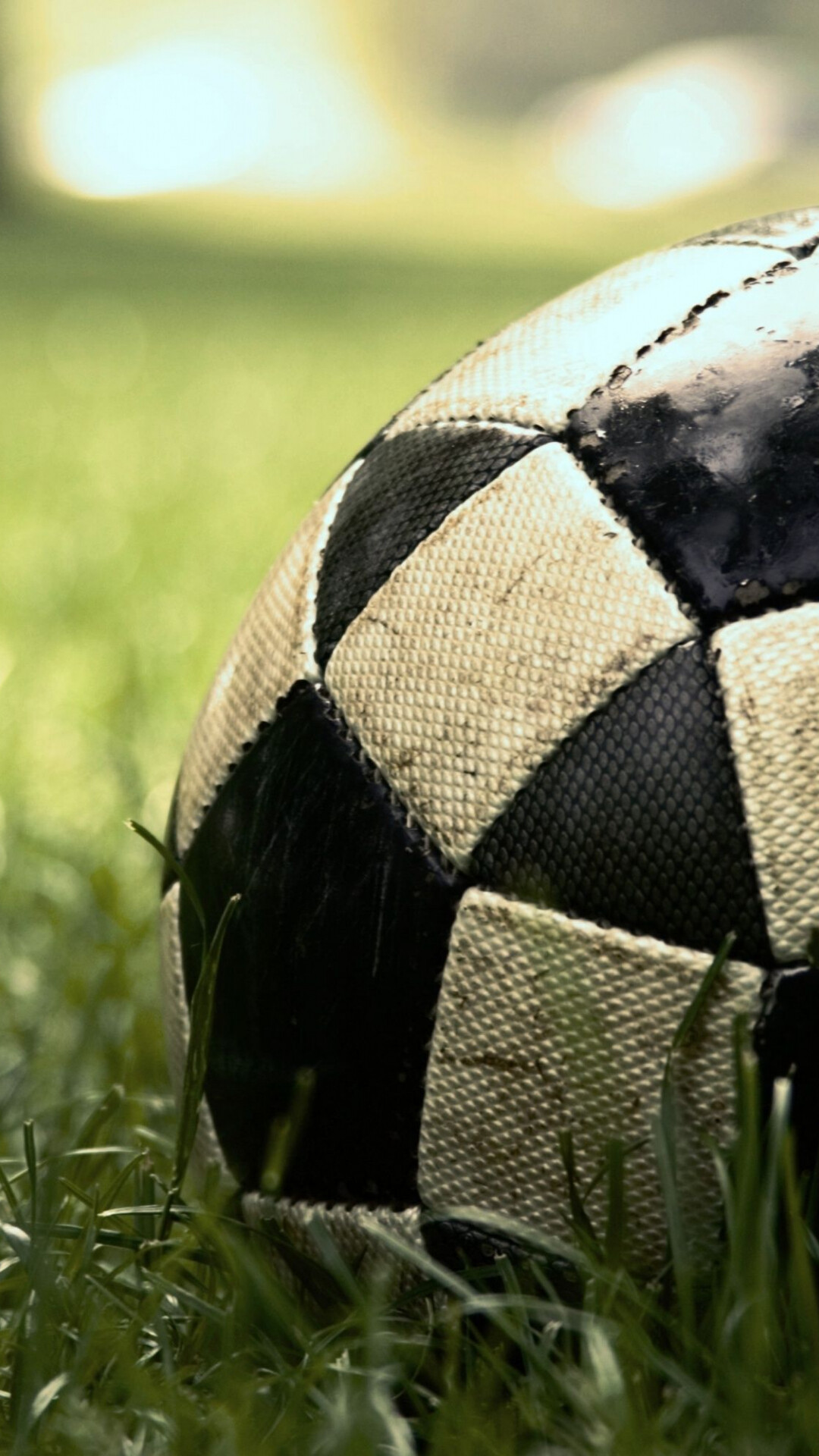 Worn black-white soccer ball, Green grass field, Blurred stadium lights Worn black-white soccer ball, Green grass field, Blurred stadium lights — 1080×1920 HD wallpaper