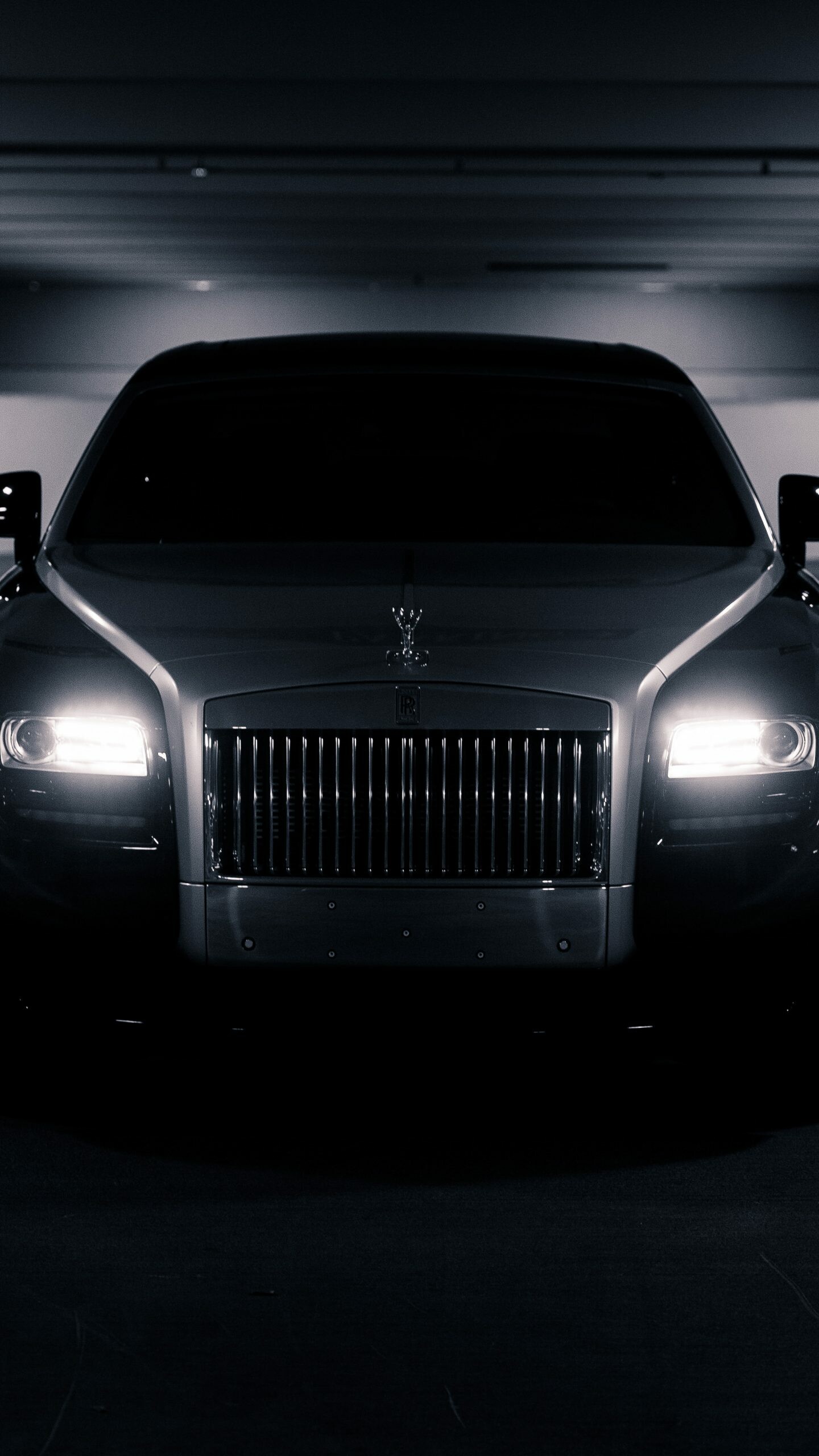 Rolls-Royce Ghost front view, Vertical Pantheon grille slats, Glowing headlights in dark garage Rolls-Royce Ghost front view, Vertical Pantheon grille slats, Glowing headlights in dark garage — 1440×2560 HD wallpaper