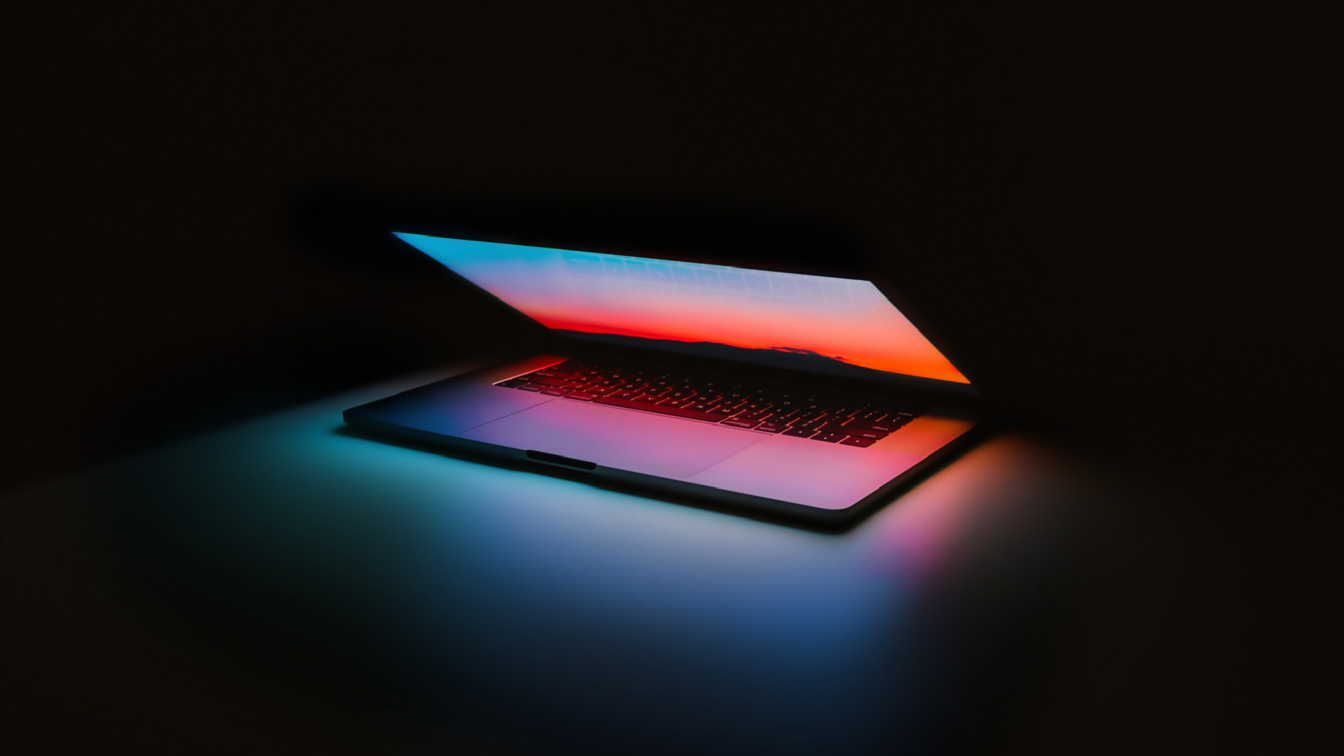 Half-open MacBook Pro, Sunset gradient screen, Dark room glow Half-open MacBook Pro, Sunset gradient screen, Dark room glow — 1920×1080 HD wallpaper